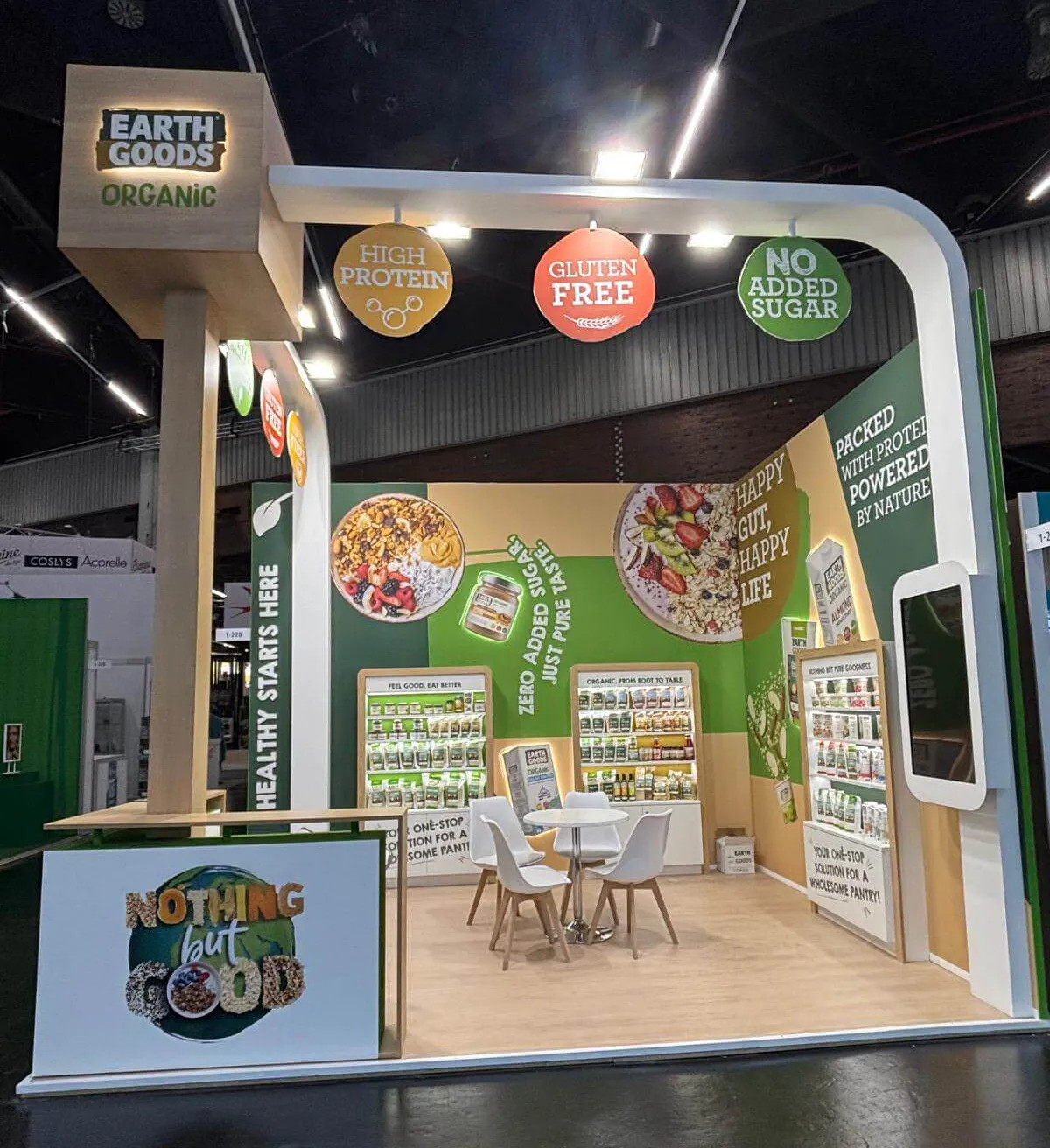 Stand para Earth Goods en la feria Biofach de alimentación ecológica en Núremberg, con una pared verde mostrando snacks orgánicos y mensajes de vida saludable – diseñado y construido por Sinergia Events
